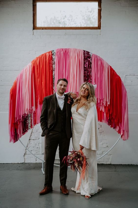 a colorful streamer wedding backdrop is a fantastic idea for a modern bright or disco themed wedding