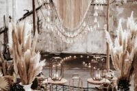 06 a neutral boho western wedding backdrop with fringe and tassels on the arch, pampas grass and greenery, candle lanterns