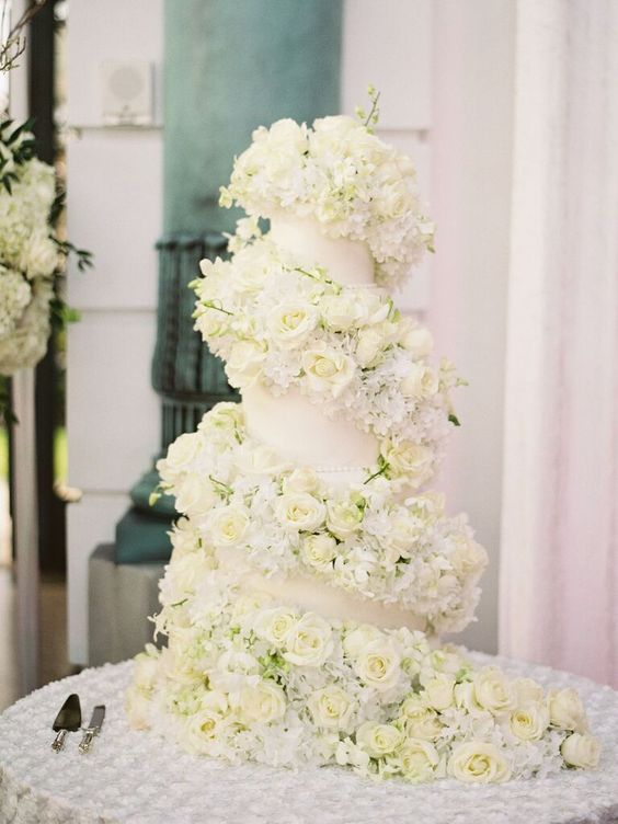 a neutral wedding cake with an oversized white rose swirl around it is a very chic and cool idea for a refined neutral wedding