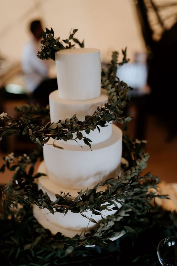 a sleek white wedding cake with eucalyptus spirals around looks jaw-dropping and will be a perfect match for a modern wedding