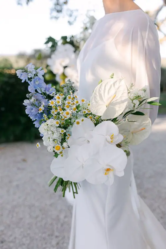 a catchy modern wedding bouquet of white chamomiles, orchids, blue blooms and white anthurium is a gorgeous idea