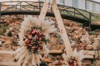 09 a western wedding arch with bright blooms, greenery and pampas grass, with a skull decorated with blooms on top