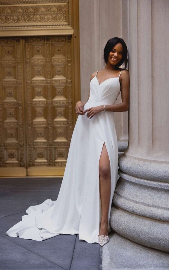 a fitting spaghetti strap wedding dress with a draped bodice, a pleated skirt with a slit and a train plus embellished shoes
