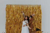 10 a fun modern wedding backdrop of gold tinsel streamers and some blooms in bottles is a cool piece to DIY