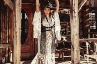 11 a catchy western bridal look with a lace applique wedding dress with bell sleeves and a train, a black leather corset with long fringe and a black embellished hat