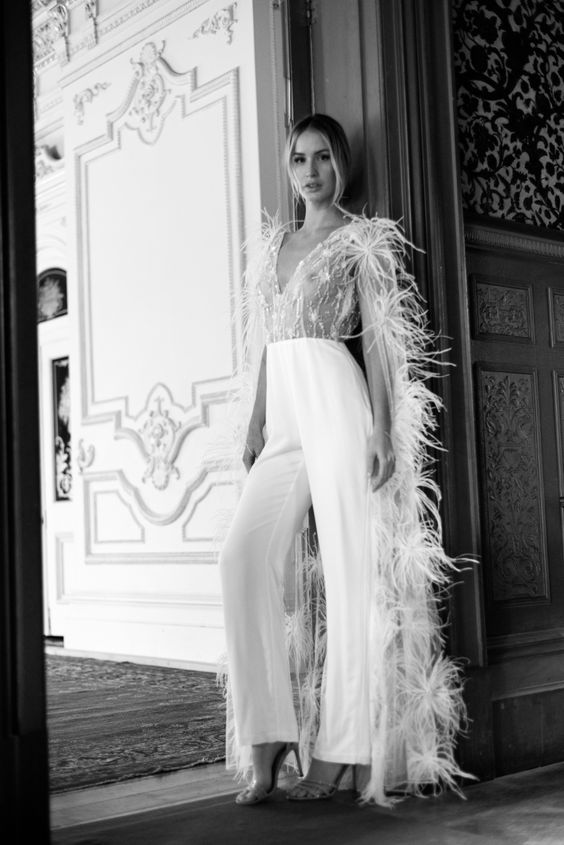 a gorgeous wedding jumpsuit with a lace embellished bodice and plain pants plus a feather capelet are a gorgeous fashion forward combo