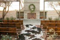 11 a western wedding ceremony space with a fireplace, firewood storage, cowhides, benches, baskets and greenery is welcoming
