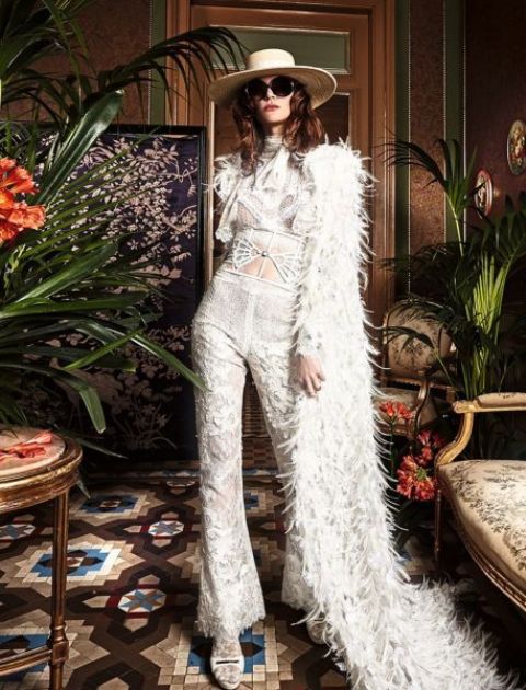 a jaw-dropping bridal look with a lace applique jumpsuit and a feather cover up with a train for a fashion-forward bride