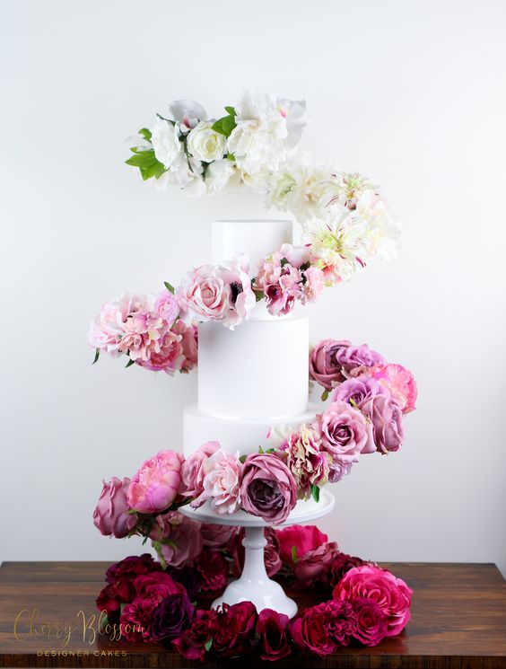 a white wedding cake with an ombre flower swirl around it, from white to bold fuchsia, is a fantastic idea to rock