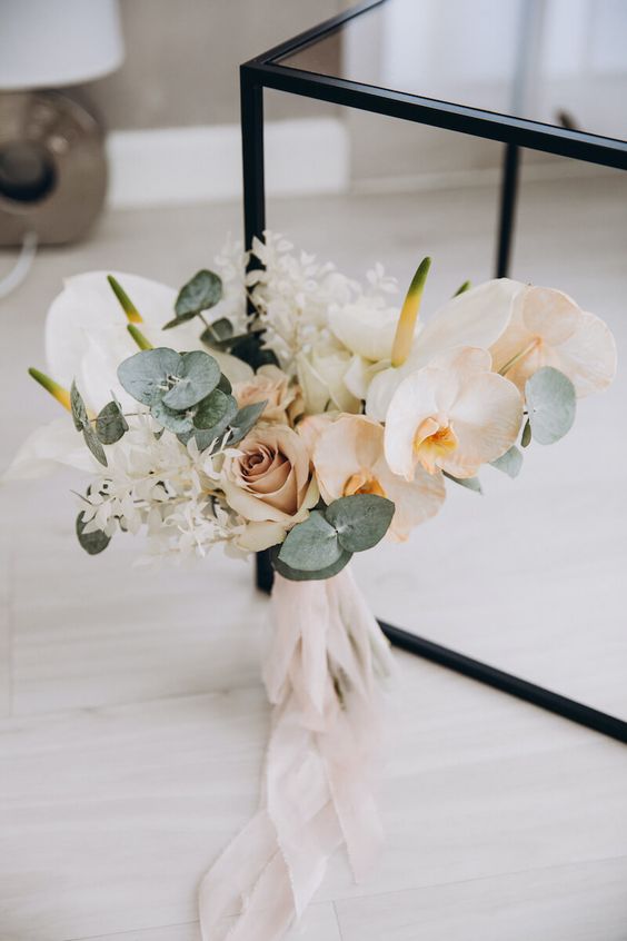 a lovely modern wedding bouquet of peachy and mauve roses and orchids, dried leaves and eucalyptus, anthurium is a chic idea