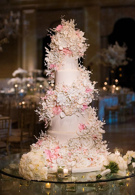 a blush wedding cake with blush and pink sugar bloom swirls around it is a very chic and cool idea for a pastel wedding