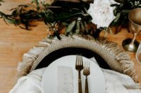 15 a boho western wedding place setting with a woven placemat, black and white plates, neutral linens, fronds and white blooms