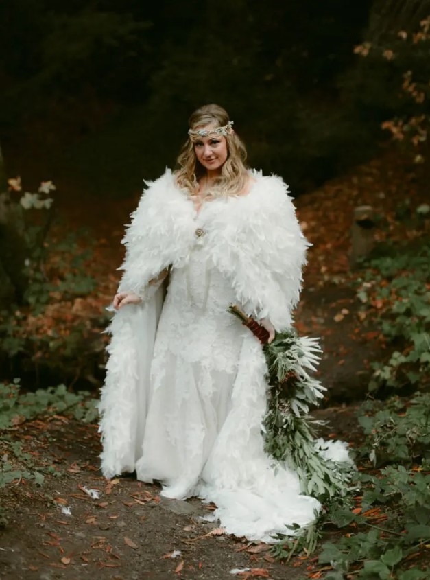 a lace sheath off the shoulder wedding dress with a train, a feather coverup, an embellished boho headpiece for a fairy tale bride