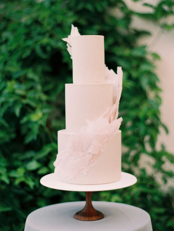 a blush wedding cake with matching sugar swirls around is a very chic and delicate idea for a pastel wedding