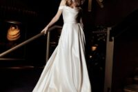 16 a modern off the shoulder wedding ballgown with a draped neckline and a draped skirt with a long train is refined and chic
