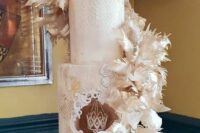 17 a dramatic neutral wedding cake with patterns and gold touches and a hanging crown inside plus neutral feather swirls around