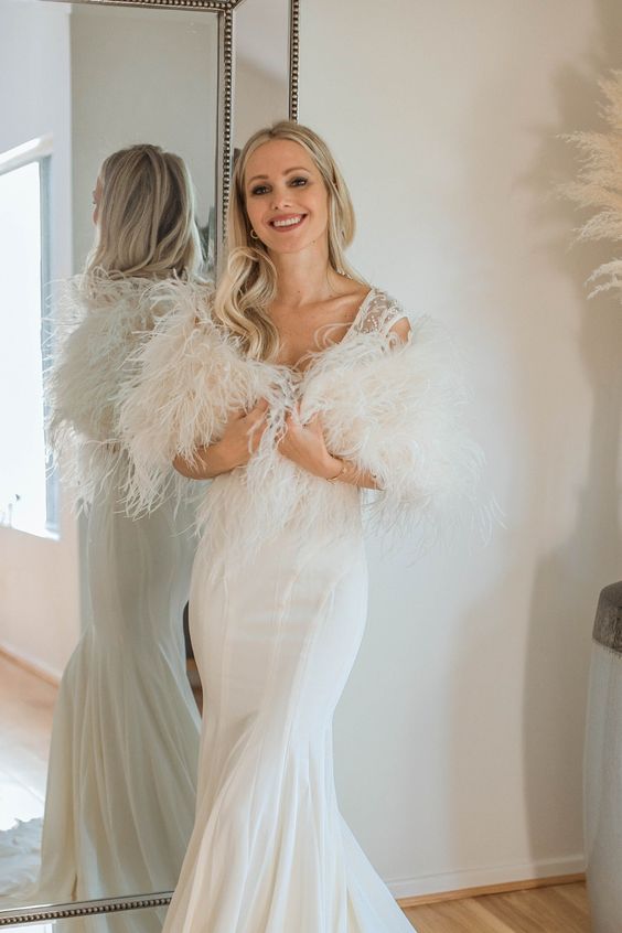 a mermaid wedding dress paired with a feather cover up are a super chic and beautiful combo for a glam bride