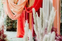 a gorgeous colorful wedding backdrop of bright drapes, pampas grass and dried blooms in various colors is wow