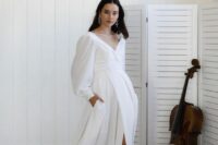 18 a modern wedding dress with a draped bodice and puff sleeves, a pleated skirt with a slit and a train plus flats and statement earrings