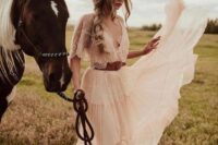 18 a romantic western bridal look with a delicate A-line wedding dress with a lace bodice and a pleated skirt, a brown hat with embroidery
