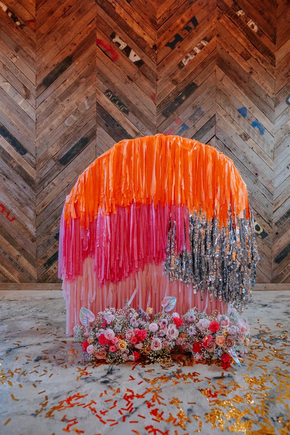 a super colorful wedding streamer backdrop with matching colorful blooms is a gorgeous idea for a bold modern wedding