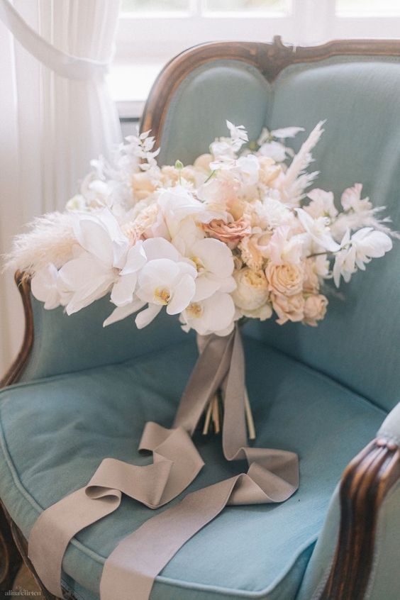 an airy neutral wedding bouquet with orchids, roses, peony roses, dried grasses and blooms is lovely for a neutral wedding