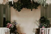 19 a beautiful wedding ceremony space done with pink and white blooms and greenery, neutral and gold streamers over the space and petals on the floor