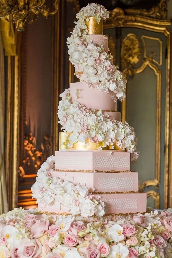 a pink hexagon and round wedding cake with white and pink bloom spirals around plus gold touches here and there