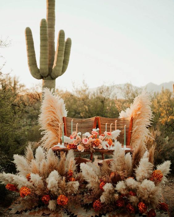 a bright western wedding sweetheart table styled with rust and blush blooms, pampas grass, pastel candles and woven chairs