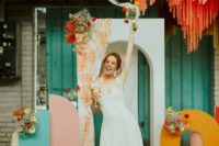 20 a colorful and artful wedding backdrop with orange, blue and pink pieces, colorful streamers, blooms and candles is amazing