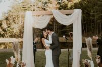 20 a modern boho wedding backdrop with neutral drapes, white vases with pampas grass and fronds is a lovely idea for a wedding