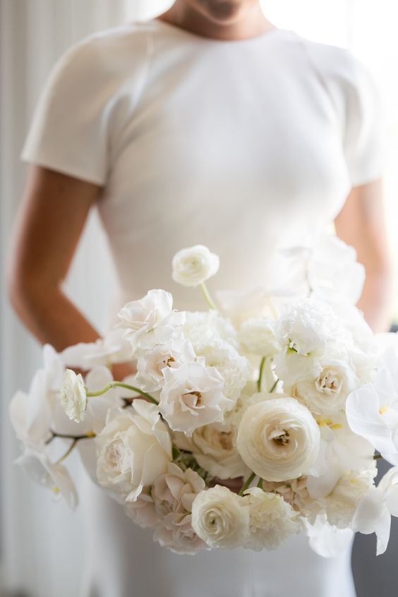 a stylish white wedding bouquet of ranunculus and roses is a lovely idea for any all-white wedding