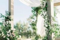 22 a neutral wedding arbor with greenery, white blooms and drapes is a very chic and beautiful idea for a wedding