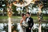 23 a neutral wedding arch with white drapes, white blooms and greenery, white candle lanterns is a lovely and timeless idea for a wedding