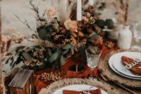 23 a pretty bright western wedding table setting with a rust table runner, woven chargers, white plates, rust napkins, fresh blooms, greenery and dried grasses