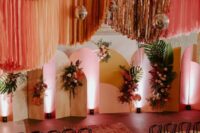 24 a jaw-dropping colorful wedding ceremony space with bright backdrops, blooms and fronds, colorful streamers over the space and cool chairs
