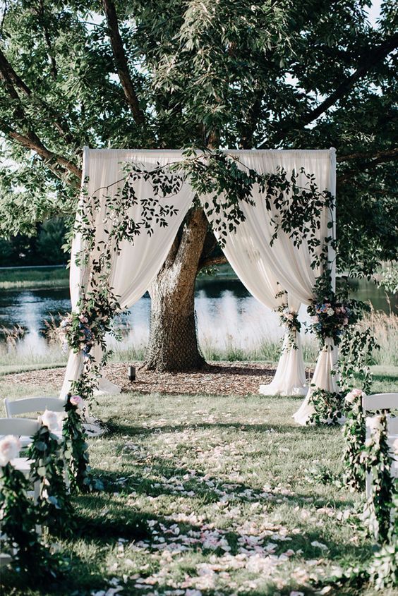 a neutral wedding backdrop with greenery is a lovely idea for outdoors, it looks beautiful and romantic