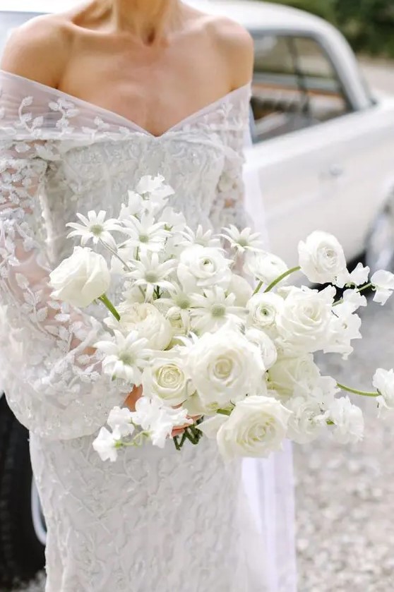 a pretty white wedding bouquet of roses and chamomiles is an unusual idea for a modern bride