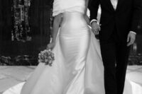 25 a sophisticated off the shoulder fitting wedding dress with a draped neckline, a large skirt with a train is a bold solution