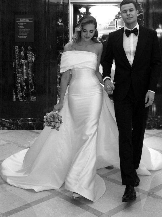 a sophisticated off the shoulder fitting wedding dress with a draped neckline, a large skirt with a train is a bold solution