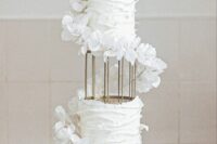 25 a white textural tiered wedding cake with a metal stand in the center, with white flower swirls around the cake is jaw-dropping