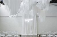 25 an all-white wedding ceremony space with white streamers, white chairs and blooms, a white curtain with a neon sign