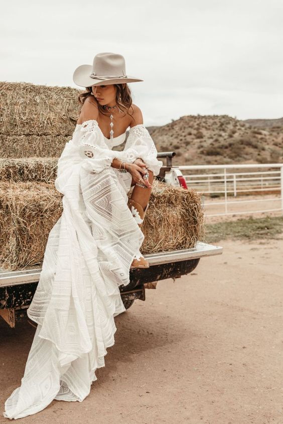 an off the shoulder boho lace wedding dress with puff sleeves, statement accessories and a neutral hat plus amber cowboy boots
