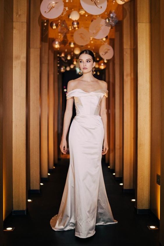 a sophisticated silk off the shoulder wedding dress with a draped neckline, a corset and a skirt with a train is jaw-dropping