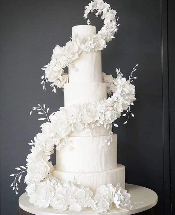 a white textural wedding cake with a swirl of white blooms and leaves is a very refined and chic idea for a modern formal wedding