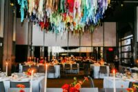 27 a bright wedding reception space with bold blooms and colorful streamers over the space is a super fun and cool idea
