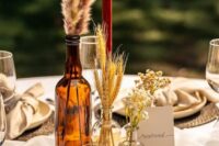27 a western wedding centerpiece of a wood slice, a candle, bottles with dried grasses and a card is a lovely and easy to DIY arrangement