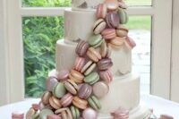 27 a white wedding cake with silver leaf decor and bright macaron swirls around is a very eye-catchy and cool idea