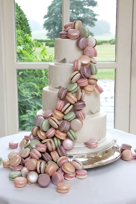 a white wedding cake with silver leaf decor and bright macaron swirls around is a very eye-catchy and cool idea