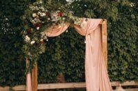 28 a refined wedding arch with pink fabric, greenery, red and white blooms and bulbs, candle lanterns and pillar candles
